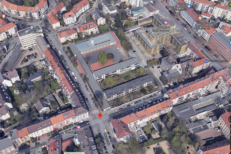 Luftaufnahme eines Schulhausareals mit modernen Gebäuden und Innenhöfen in einem urbanen Wohngebiet.