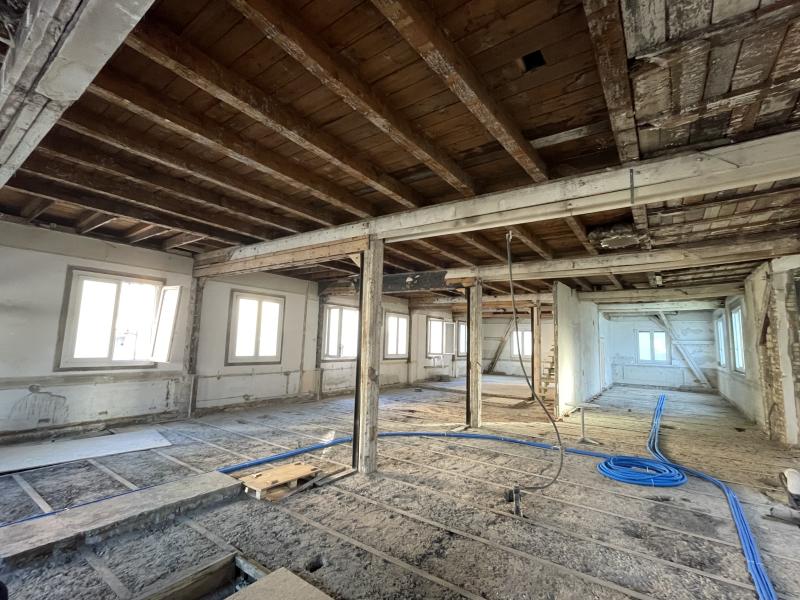 Rohbau eines Wohngebäudes mit tragenden Holzbalken und Fensteröffnungen im Umbau.