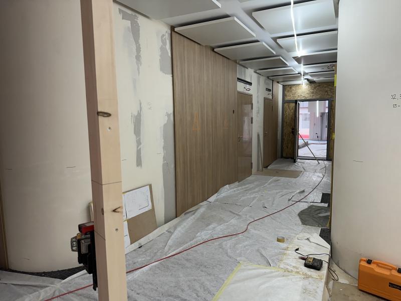 Innenraum einer Baustelle mit Holzverkleidungen, Schutzfolien und Bauwerkzeugen.