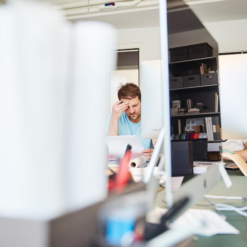 Hannes Reichel sitzt an einem Schreibtisch in einem modernen Büro und arbeitet am Laptop.