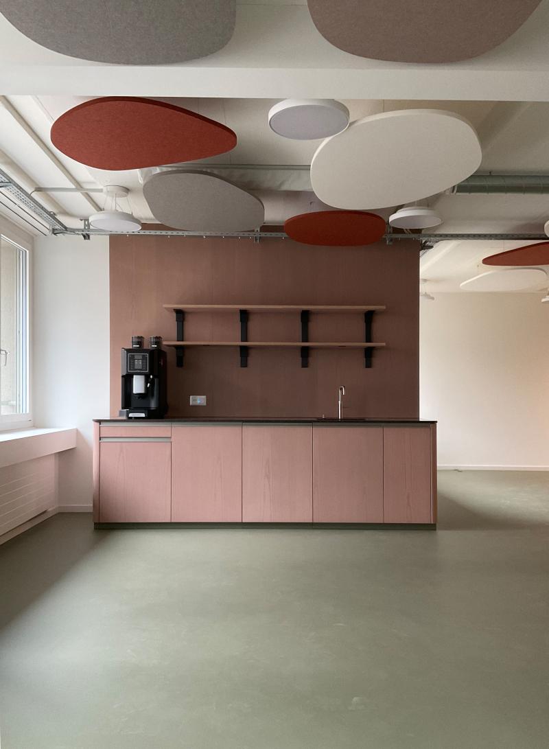Büroraum mit rosafarbenen Schränken und roten Akustikpaneelen an der Decke im Hochhaus Hoch3 für die Genossenschaft ABZ.