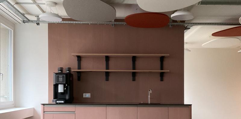 Büroraum mit rosafarbenen Schränken und roten Akustikpaneelen an der Decke im Hochhaus Hoch3 für die Genossenschaft ABZ.