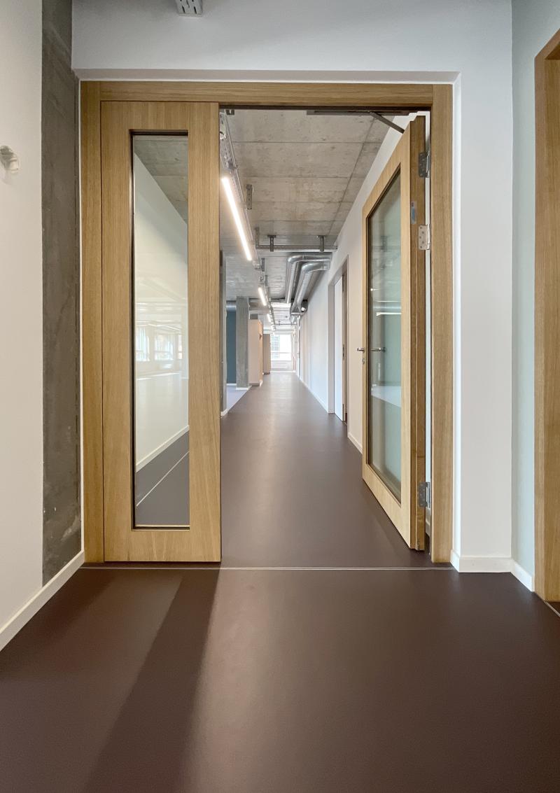 Flur mit Glastüren und Holzrahmen im Hochhaus Hoch3 der Genossenschaft ABZ in Zürich-Wiedikon.