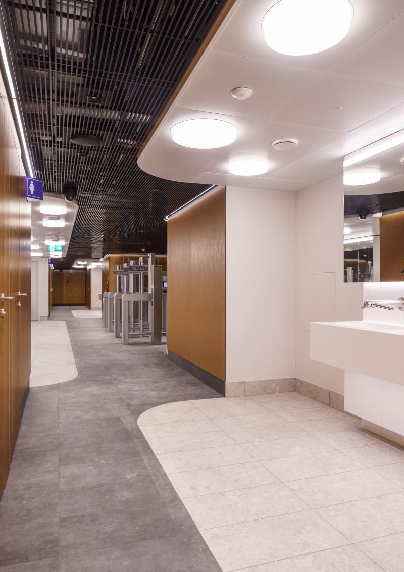 Flurbereich mit weißen Rundleuchten und Holzverkleidung im Hygienecenter des Zürcher Hauptbahnhofs.