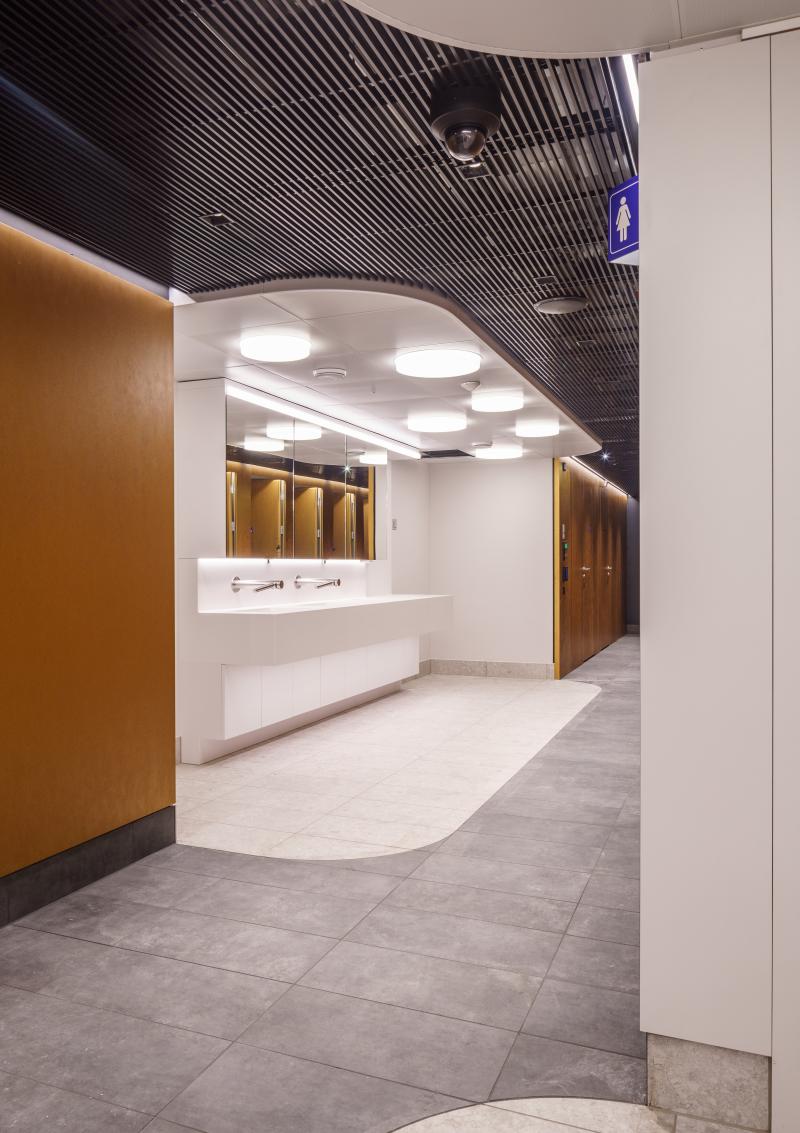 Empfangsbereich des Hygienecenters im Zürcher Hauptbahnhof mit geschwungener Decke und Informationstheke.