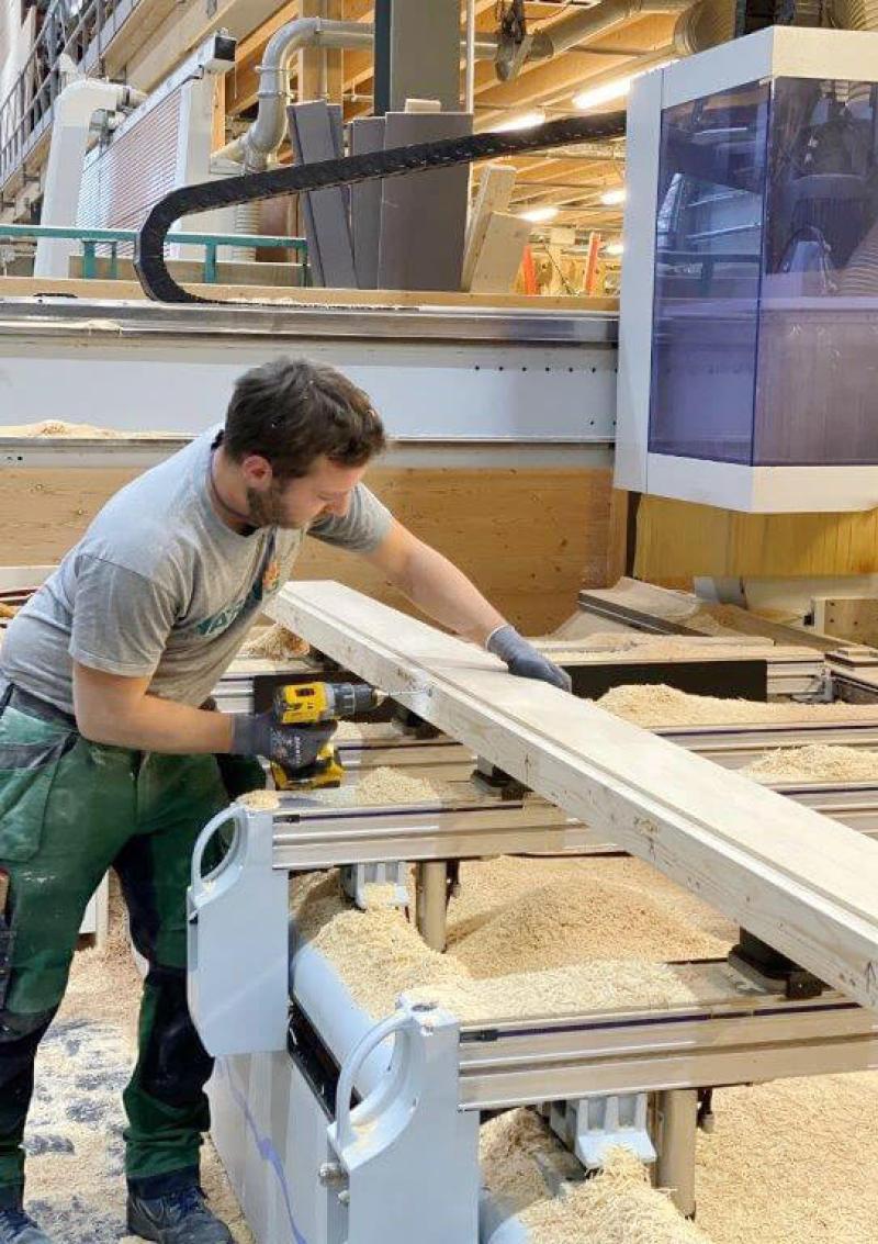 Ein Handwerker bearbeitet ein Holzfassadenelement für den Doppelkindergarten Werd in Adliswil.