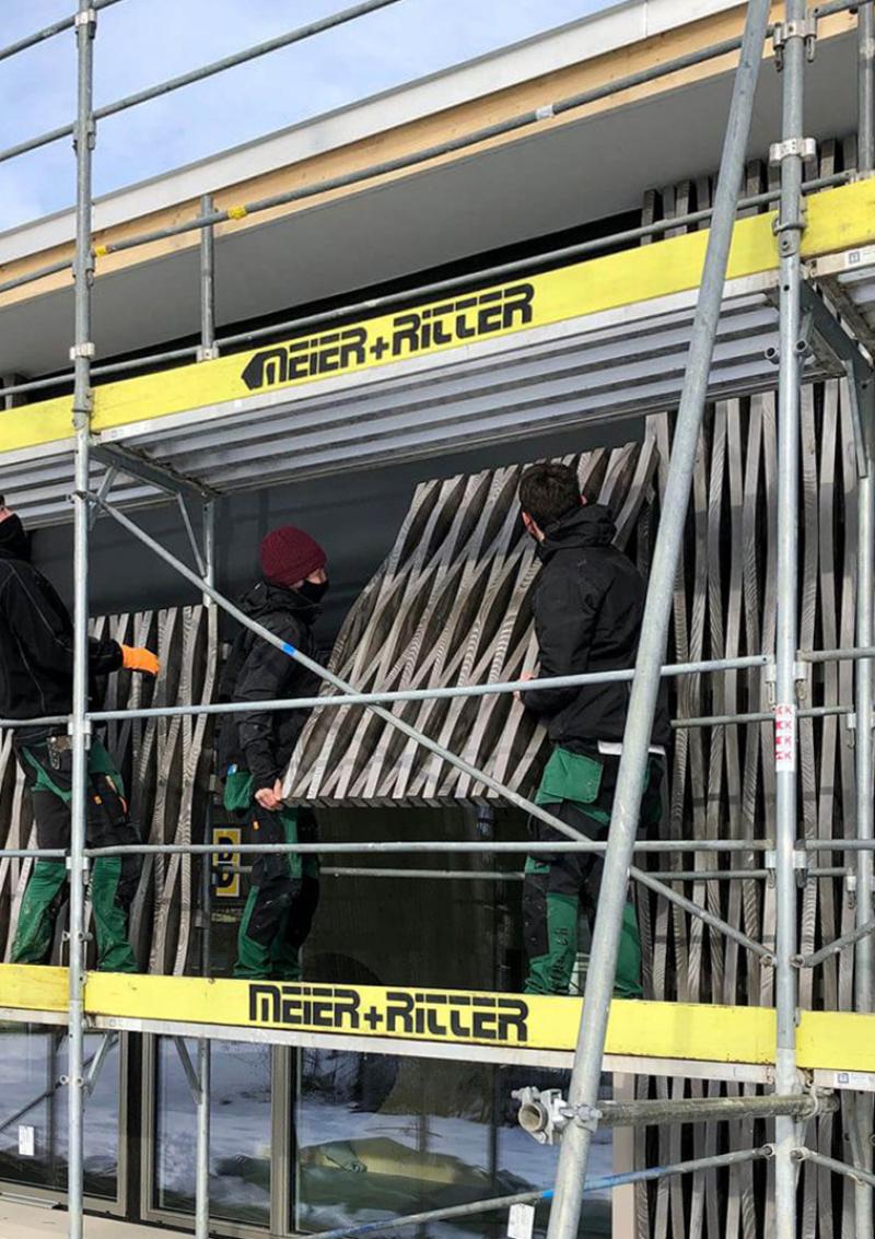 Holzfassade mit vertikaler Gliederung und Gerüstung beim Doppelkindergarten Werd in Adliswil.