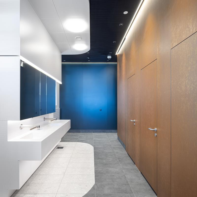 Modernisierter Sanitärbereich mit blauer Akzentwand und Holzverkleidung in den Kundenbereichen der SBB.