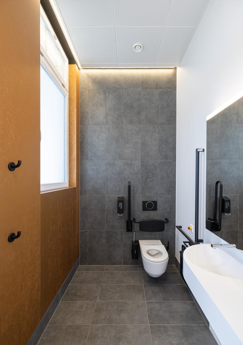 Modernes Badezimmer mit grauer Fliesenverkleidung und weißem Waschbecken in den Kundenbereichen der SBB.