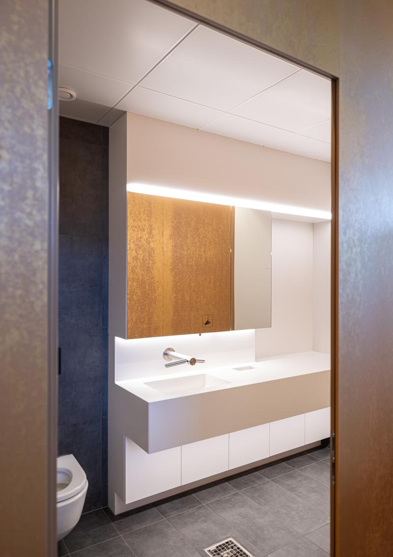 Modernes Badezimmer mit weißem Waschbecken und Spiegelbeleuchtung in den Kundenbereichen der SBB.