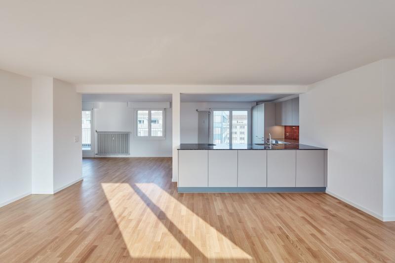 Wohnzimmer mit Holzboden und offener Küche in einem Mehrfamilienhaus in Luzern.