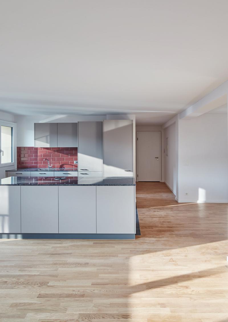 Offene Wohnküche mit Kücheninsel und Holzboden in einem sanierten Mehrfamilienhaus in der Luzerner Innenstadt.