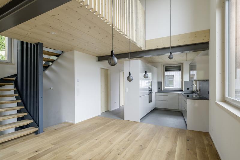 Offener Wohnbereich mit Holzdecke und Küchenzeile in einem Mehrfamilienhaus in Adliswil.