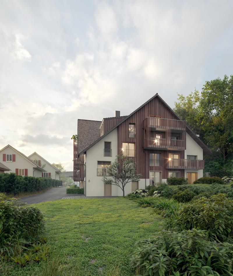 Mehrfamilienhaus Manzelnweg in Tägerig mit asymmetrischer Fassade aus Holz und Putz auf grüner Wiese.