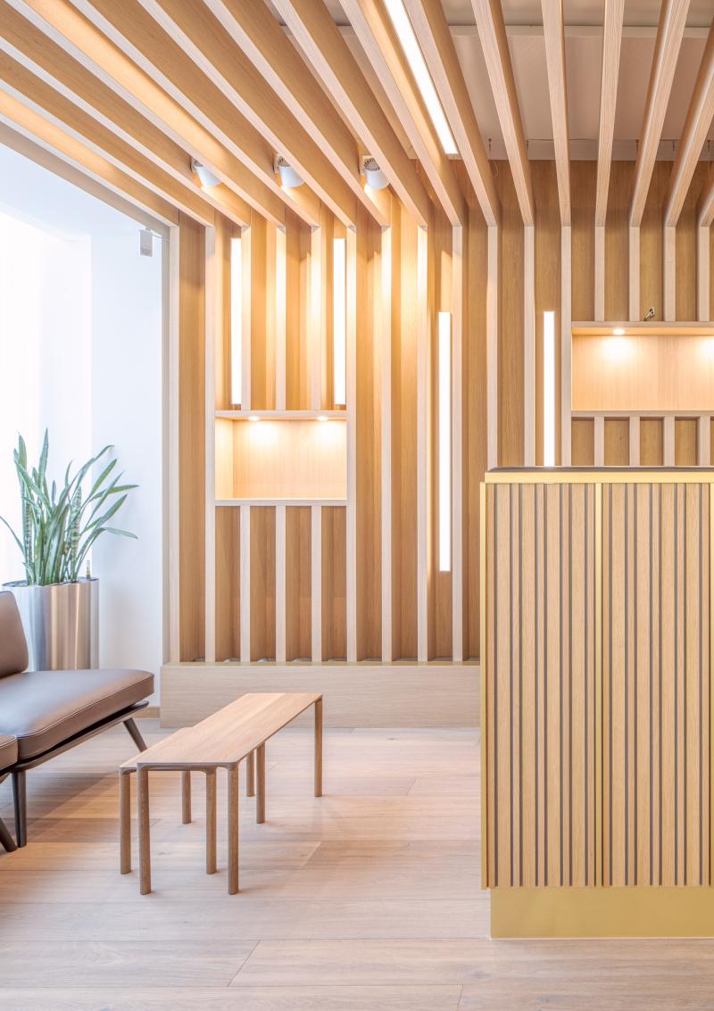 Moderner Wartebereich mit Holzlattenverkleidung und minimalistischen Möbeln in der Privatbank Zürich.