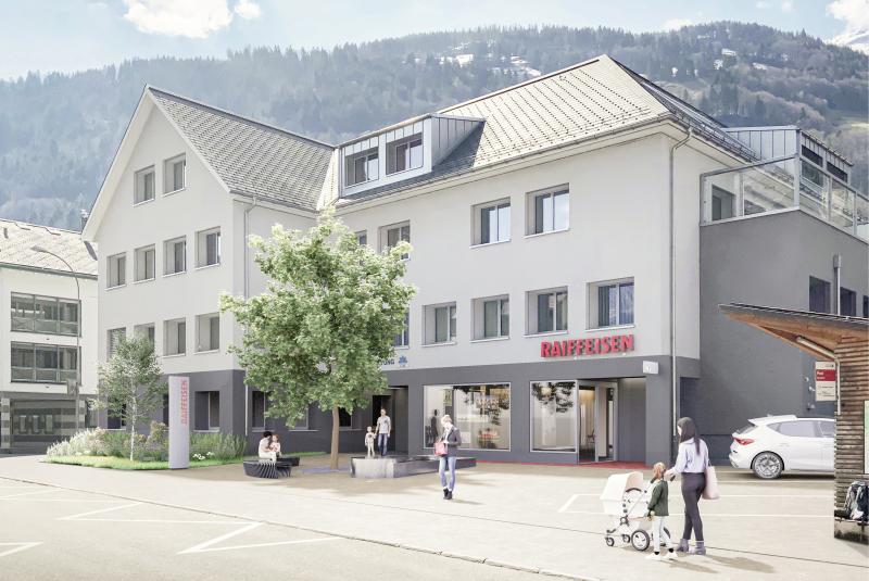 Neugestaltete Raiffeisenbank-Filiale Muotathal mit weisser Fassade, Metalldach und ebenerdiger Ladenzone in alpiner Umgebung.