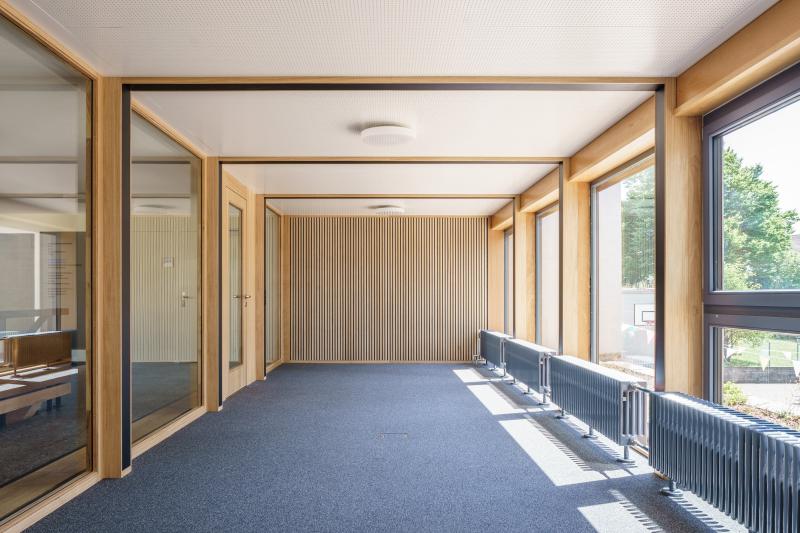 Heller Flur mit Holzrahmen und Sichtbetonwänden im ehemaligen Jugendheim Erika an der Rötelstrasse in Zürich-Wipkingen.