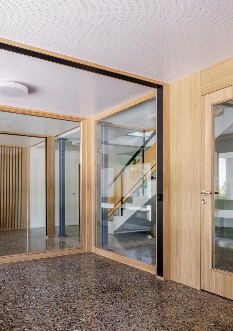 Eingangshalle mit Holzverkleidung und Glasschiebetüren zum ehemaligen Jugendheim Erika an der Rötelstrasse.