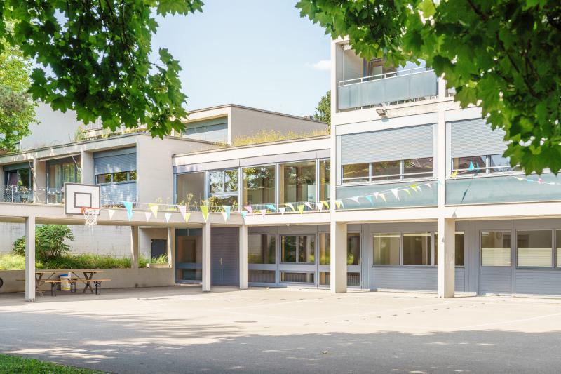 Fassade des ehemaligen Jugendheim Erika an der Rötelstrasse in Zürich-Wipkingen mit Sichtbetongebäuden und Vorplatz.