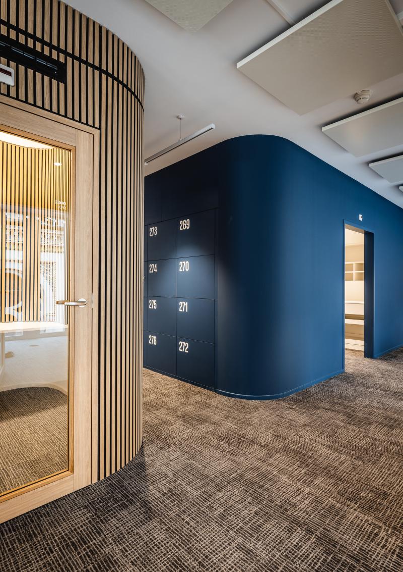 Flur mit dunkelblauer geschwungener Wand und Holztrennwand in einem Bürogebäude am Raiffeisenplatz St. Gallen.