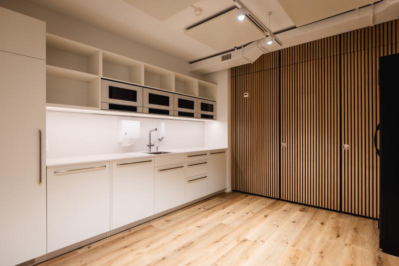 Moderne Büroküche mit weißen Schränken und Holzboden für eine Unternehmensberatung am Raiffeisenplatz in St. Gallen.